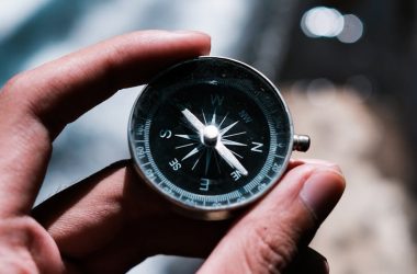 a person holding black and silver compass