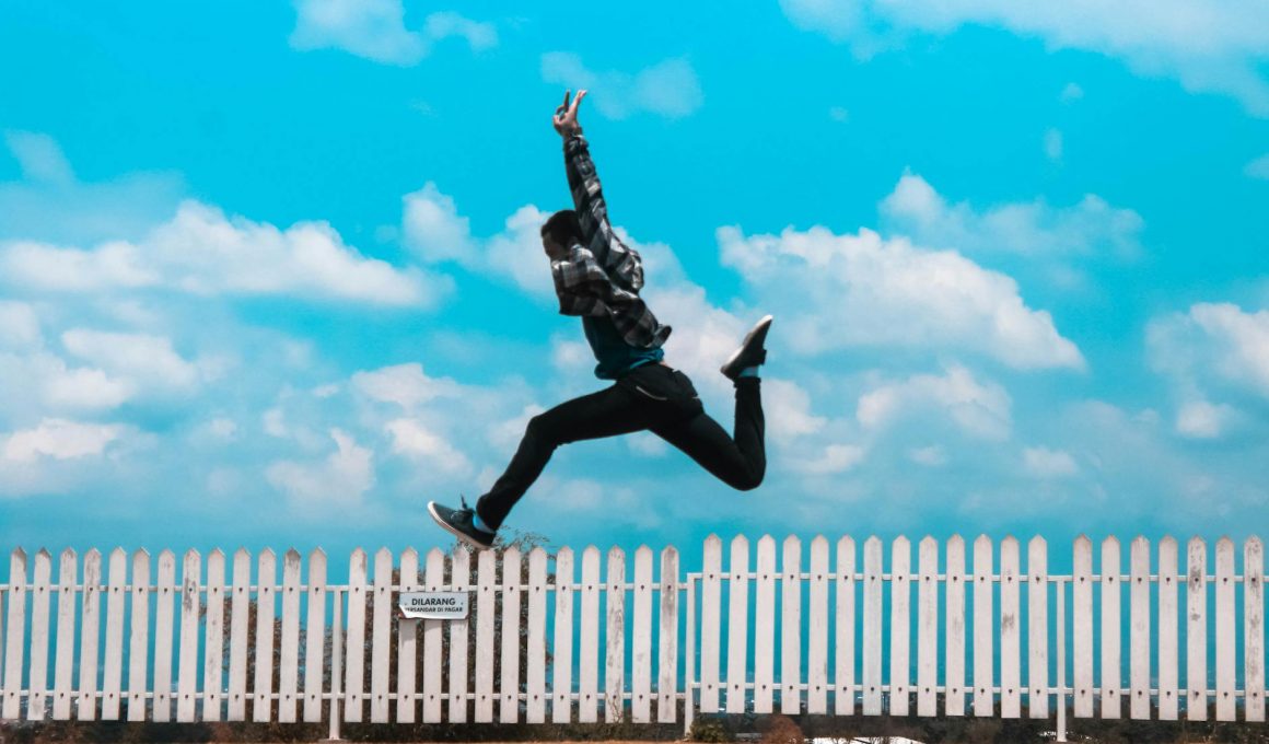 man jumping over white fence