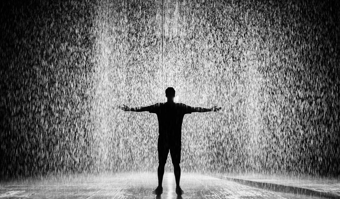 silhouette and grayscale photography of man standing under the rain