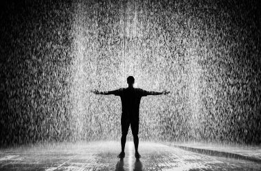 silhouette and grayscale photography of man standing under the rain