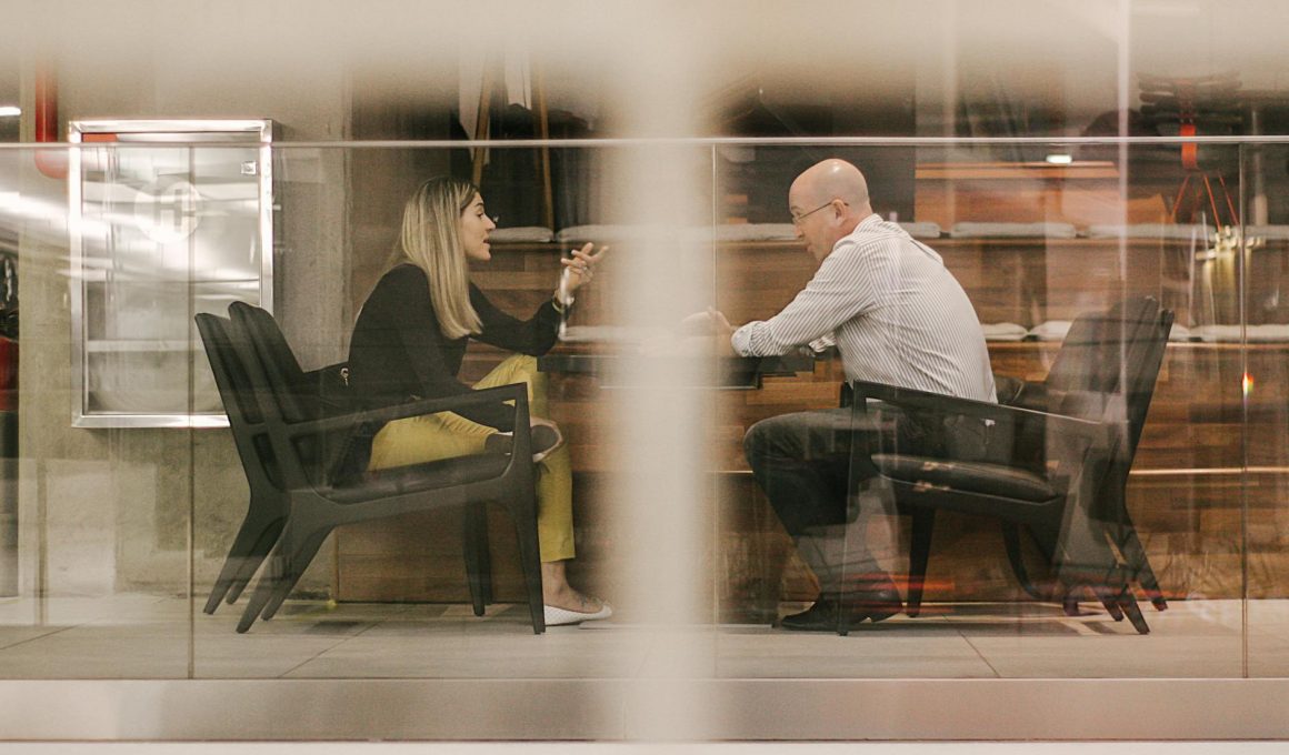 man and woman sitting on black wooden chairs
