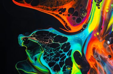 colorful mix of neon paints swirling on black surface