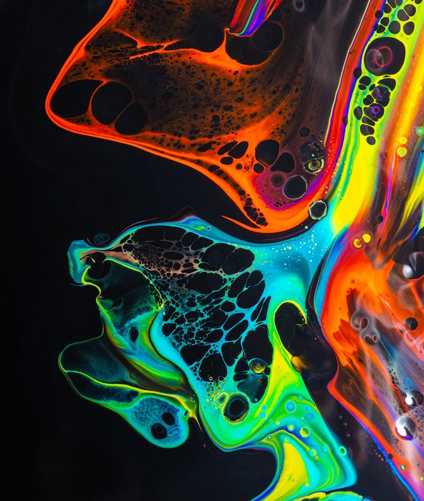 colorful mix of neon paints swirling on black surface