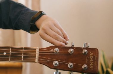person playing brown acoustic guitar