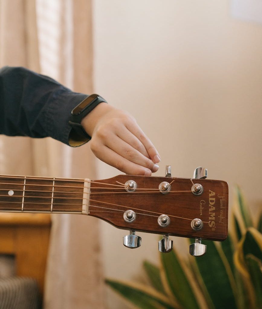 person playing brown acoustic guitar